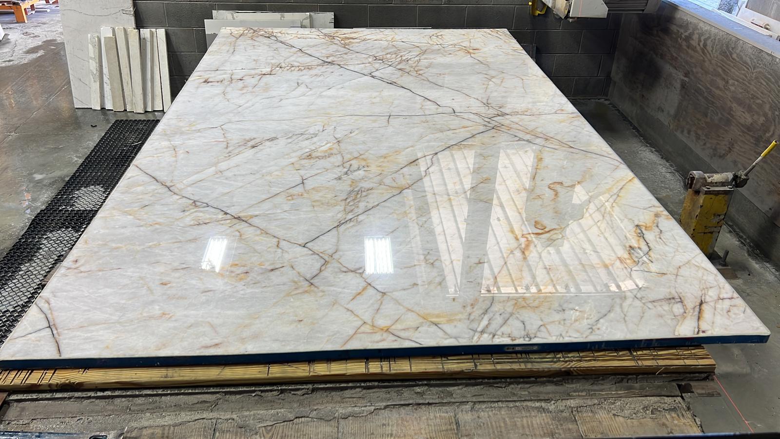 Polished gold-veined slab on the saw table